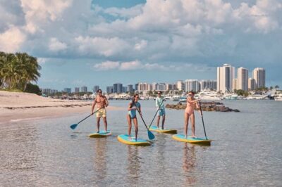 amigos paddleboarding na peanut island. créditos para discover the palm beaches.