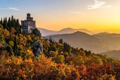 Castelo medieval em meio às cores do outono nas montanhas, panorama deslumbrante na Toscana, Itália, ao pôr do sol, viagem de turismo, destino europeu, natureza e história.