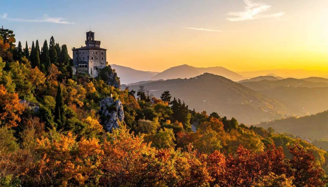 Castelo medieval em meio às cores do outono nas montanhas, panorama deslumbrante na Toscana, Itália, ao pôr do sol, viagem de turismo, destino europeu, natureza e história.