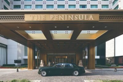 Lindo hotel de luxo The Peninsula com entrada imponente, decoração elegante e carro clássico na frente, ideal para viagens de negócios ou lazer na cidade.