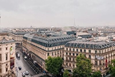 Vistas de Paris com edifícios históricos e a Torre Eiffel ao fundo, ideal para viagens e turismo na França.