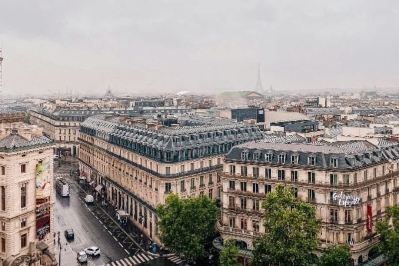 Vistas de Paris com edifícios históricos e a Torre Eiffel ao fundo, ideal para viagens e turismo na França.