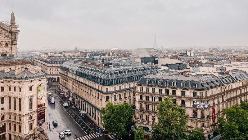 Vistas de Paris com edifícios históricos e a Torre Eiffel ao fundo, ideal para viagens e turismo na França.