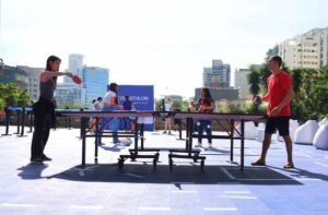 SuoViaggio esporta diversão ao ar livre com pessoas jogando pingue-pongue em ambiente urbano e com clima ensolarado, promovendo eventos de lazer e integração nas cidades brasileiras.