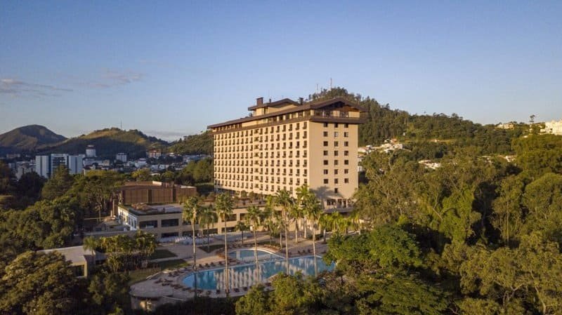 SuoViaggio hotel de luxo com piscina e vista panorâmica em área arborizada, ideal para viagens de lazer e negócios na cidade.