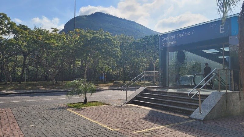 Entrada do metrô General Osório/Ipanema em Rio de Janeiro, com escadas, plataforma moderna e paisagem natural ao fundo, ideal para viagens pelo transporte público na cidade do Rio.