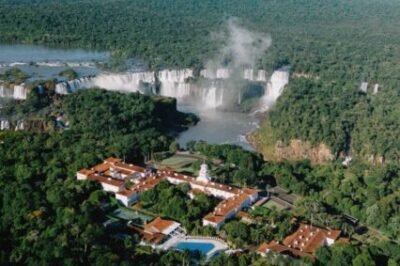 Vista aérea da Cachoeira do Iguaçu, em Foz do Iguaçu, com resort luxuoso, piscina, e ampla vegetação, ideal para turismo ecológico, viagens de lazer e aventura na natureza.