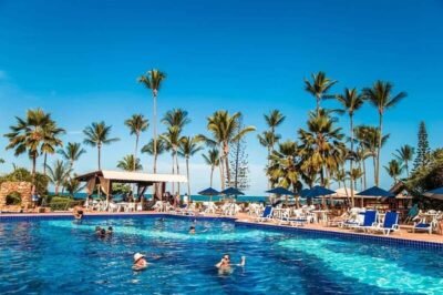 Relaxamento na piscina de resort paradisíaco com palmeiras, espreguiçadeiras e sombra para férias tropicais perfeitas em destinos de luxo.