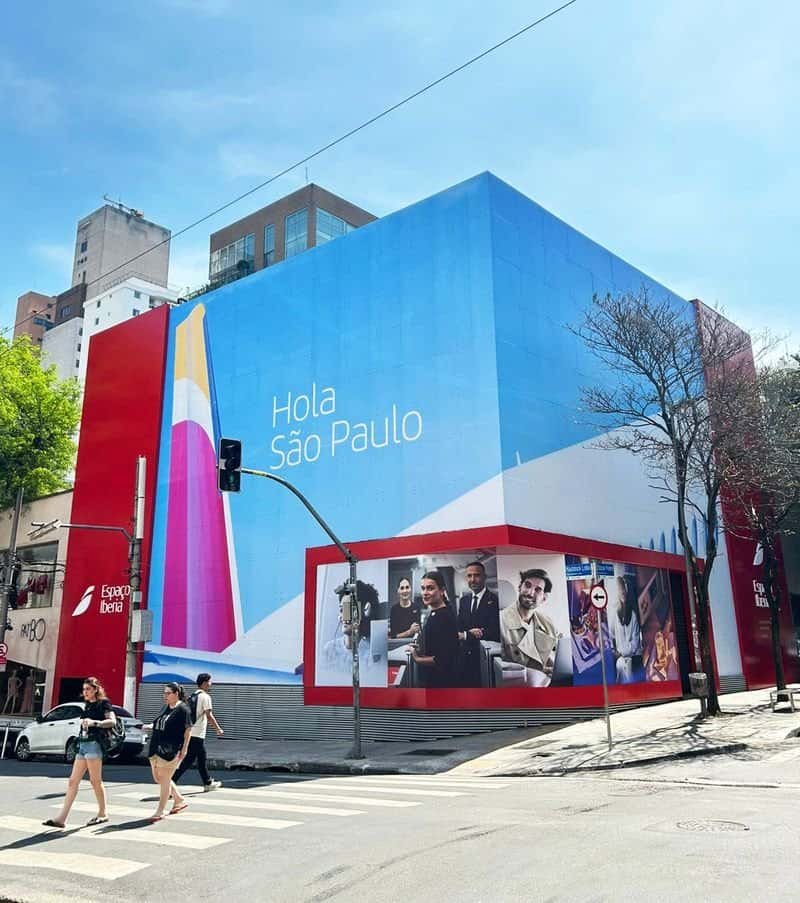 - Fachada de prédio em São Paulo com grande banner azul e mensagens acolhedoras para turistas e visitantes.
