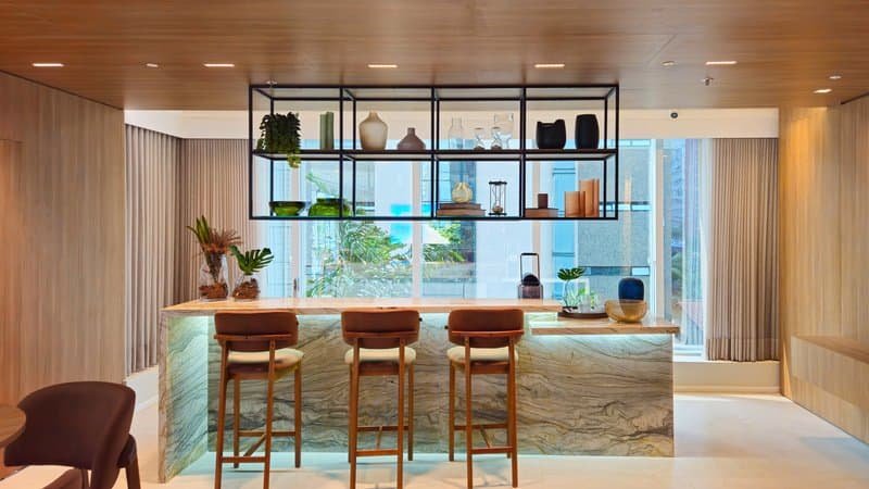 Bar de hotel elegante com bancada de mármore, cadeiras confortáveis e decoração moderna, ideal para experiências de hospedagem de alta qualidade.
