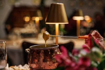 Cozinha de fondue com queijo quente em restaurante aconchegante, iluminação ambiente e decoração elegante.