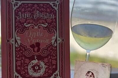 SuoViaggio - Cultura e Vinho. Luz de vinho branco ao lado do livro de Jane Austen sobre romance clássico, com vista para o mar ao fundo, ideal para viagens de lazer, leitura e apreciação de vinhos em destinos turísticos no Brasil e mundo.