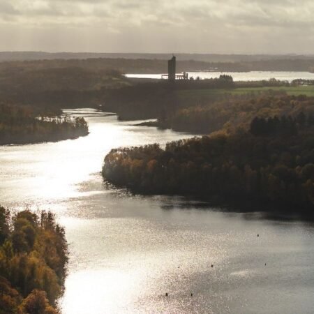 Lago com paisagem natural e torre ao fundo 1 entre sambre et meuse national park credits visitwallonia
