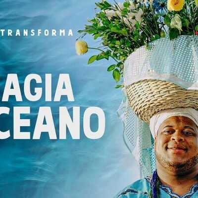 Imagem de um homem com um chapéu decorado com flores e uma cesta de palha na cabeça, simbolizando a conexão com o oceano e o turismo sustentável.